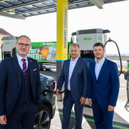 Auf dem Bild sind drei Männer in Anzügen zu sehen, die neben der neuen Ladestation stehen. Links im Bild ist Harald Großauer (Landesdirektor ÖAMTC Oberösterreich), er trägt einen dunklen Anzug mit Rot-schwarz-gestreifter Krawatte und eine Brille. Etwas weiter rechts im Bild stehen Franz Ortner und Michael Ortner (Eigentümer und Geschäftsführer Autohaus Ortner), beide tragen dunkelblaue Anzüge und hellblaue Hemden. Franz Ortner ist gerade dabei das Elektorauto aufzuladen.