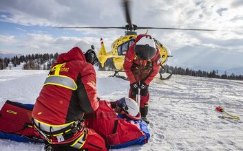 Mitarbeiter der Flugrettung beim Einsatz auf der Skipiste. Sie versorgen eine Person.