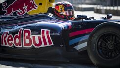 Ausschnitt eines Formel 1 Fahrzeugs mit Fahrer der einen Helm trägt.