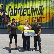 Die 150.000ste Teilnehmerin zusammen mit Zentrumsleiter Andreas Rouschal und Patricia Altmann vor einer Fahrtechnik-Graffitiwand