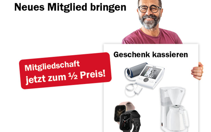 Ein Mann mit Brille und Bart hält ein Plakat mit Freundschaftswerbegeschenken in die Höhe.