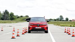 Rotes Auto testet auf einem Übungsgelände die Assistenzsysteme, Pylone begrenzen die Fahrspur.