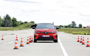 Rotes Auto testet auf einem Übungsgelände die Assistenzsysteme, Pylone begrenzen die Fahrspur.
