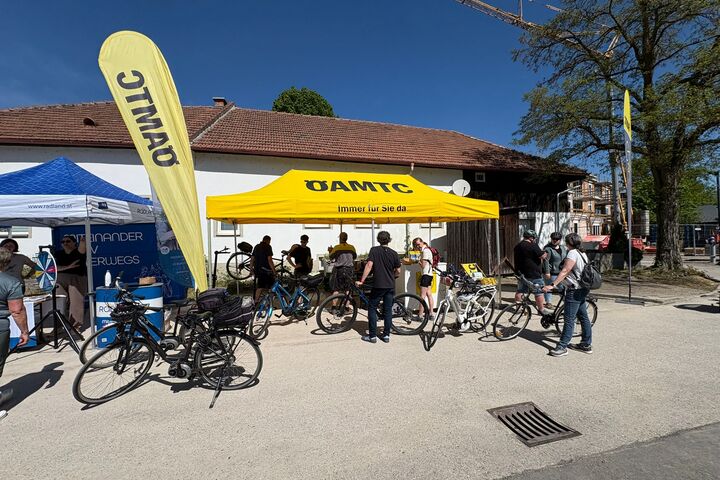 Fahrradfahrer:innen lassen sich ihre Fahrränder am ÖAMTC PopUp Fahrrad-Stützpunkt in Hofstetten-Grünau reparieren