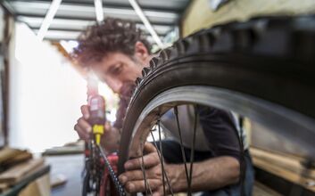 Ein Mann ölt die Fahrradkette eines Fahrrades.