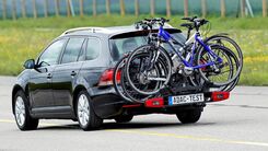 Ein ADAC-Testauto fährt auf der Straße im Testgelände. Am Auto befindet sich ein Fahrradheckträger mit drei befestigten Fahrrädern darauf.