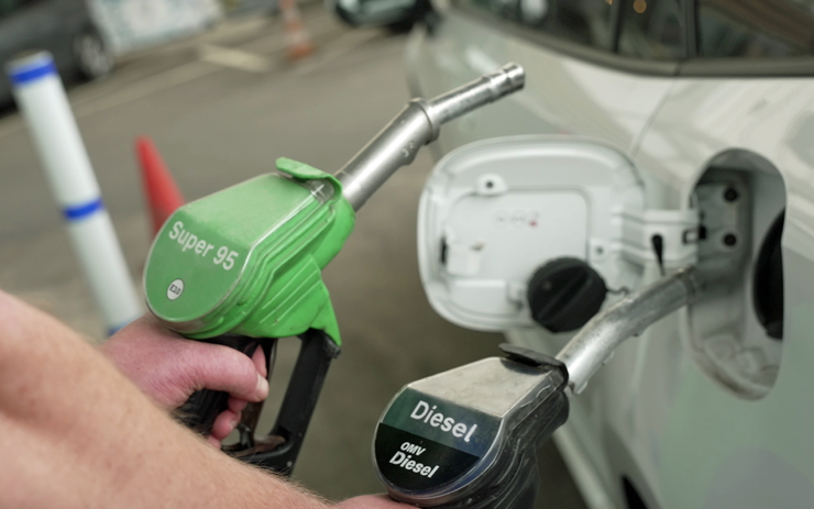 Eine Person hält zwei Tankeinfüllstutzen (Benzin und Diesel) in der Hand.
