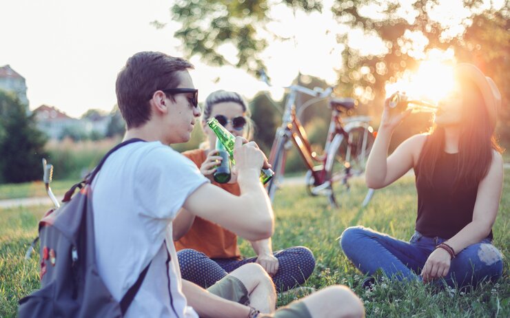 Alkohol im Sommer 3 Jugendliche sitzen im Sommer auf einer Wiese und trinken Alkohol.