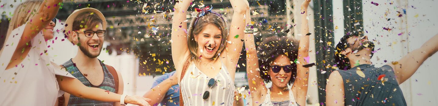 Eine Gruppe junger Menschen tanzt und feiert im Freien, umgeben von Konfetti.