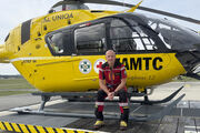 Flugretter Markus Amon sitzt in seiner Uniform vor einem Christophorus Helikopter.