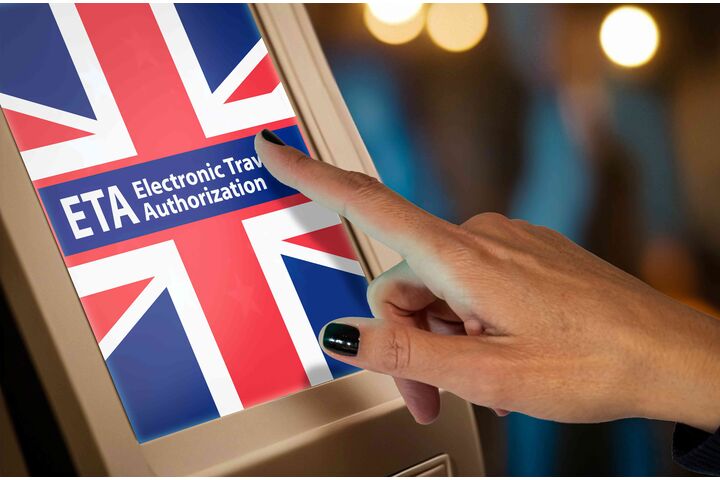Ein Bildschirm, der eine britische Flagge mit dem Schrifzug ETA Electronic Travel Authorization zeigt, und eine Hand, die den Bildschirm berührt
