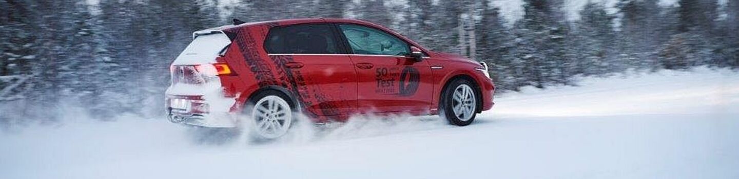 Ein rotes Auto auf Schneefahrbahn.