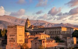 Das Foto zeigt die Alhambra in der Abendsonne vor den Gipfeln der Sierra Nevada.