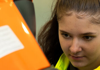 Auf dem Bild sieht man die Gesichter eines jungen Mannes und einer jungen Frau die konzentriert auf eine orangefarbene Fläche schauen