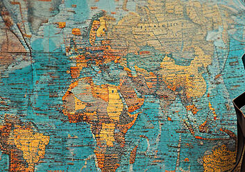 Auf dem Bild sieht man eine Weltkarte, davor steht ein Rucksack.