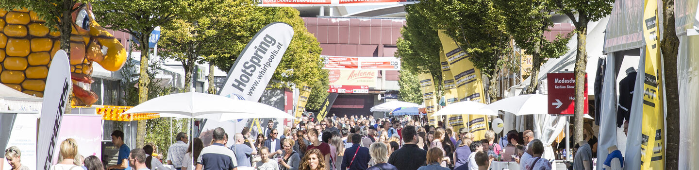 Viele Messebesucherinnen und Besucher im Freigelände einer Messe unterwegs.