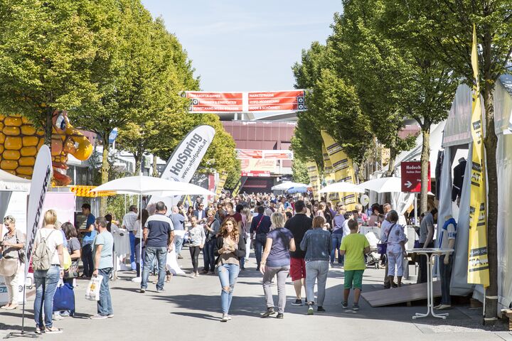 Viele Messebesucherinnen und Besucher im Freigelände einer Messe unterwegs.