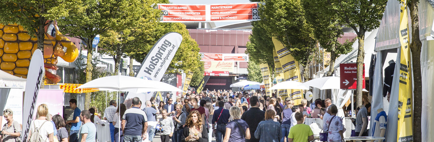 Viele Messebesucherinnen und Besucher im Freigelände einer Messe unterwegs.