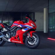 Das Foto zeigt ein Rot-Blaues Motorrad, das vor einem Gebäude steht.