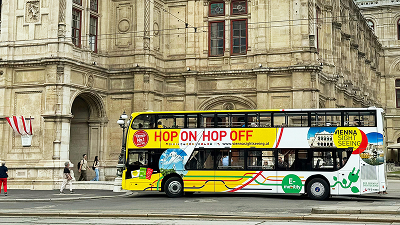 Ein Hop-On-Hop-Off-Vienna-Sightseeing-Tour-Bus fährt auf der Straße.
