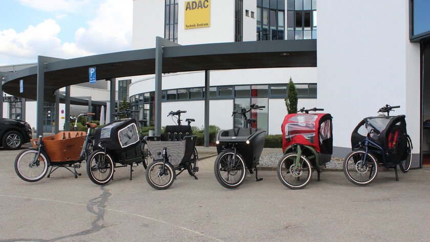 Sechs einspurige Elektro-Lastenfahrräder sind vor einem Gebäude aufgestellt.