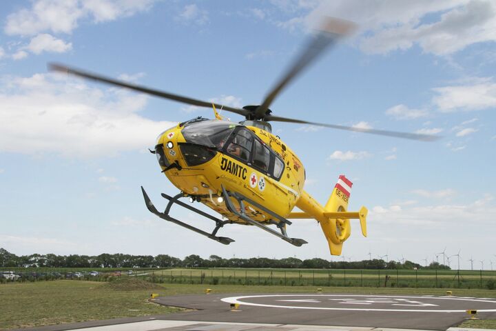Ein gelber Notarzthubschrauber hebt von seinem Landeplatz aus ab