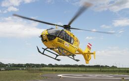 Ein gelber Notarzthubschrauber hebt von seinem Landeplatz aus ab