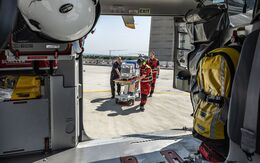 Blick aus dem Inneren des Christophorus 33-Rettungshubschraubers auf 3 Einsatzkräfte, die einen Inkubator transportieren.