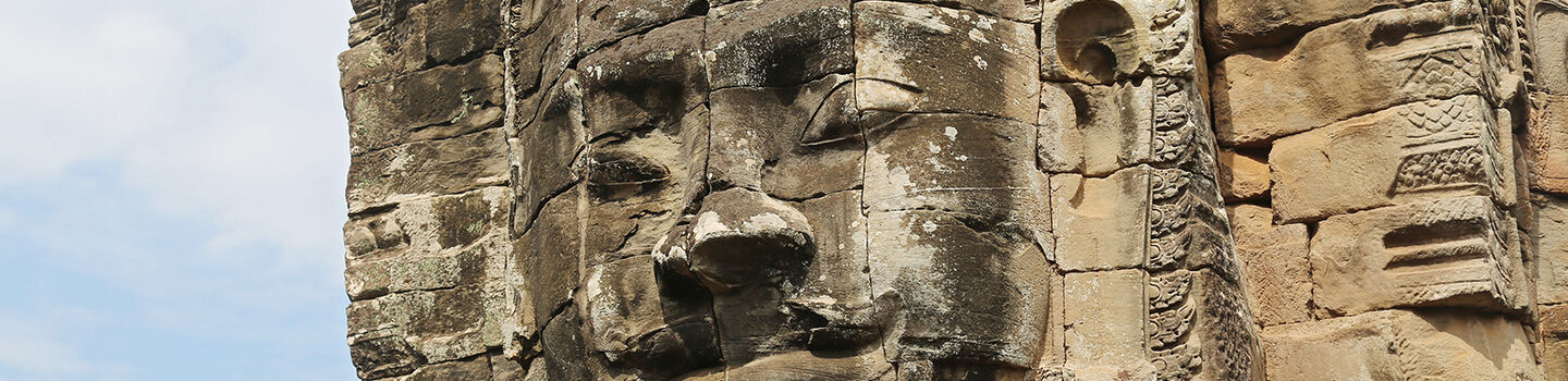 Reste einer Tempelanlage in Angkor mit einem in Stein gemeißelten Gesicht