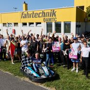 Das Ensemble der Seefestspiele Mörbisch posiert für ein spaßiges Gruppenbild vor der Boxengassengasse der Kartstrecke
