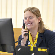 Reisebürokauffrau Katharina Wiesbauer am Telefon, wie sie auf den Computerbildschirm blickt.