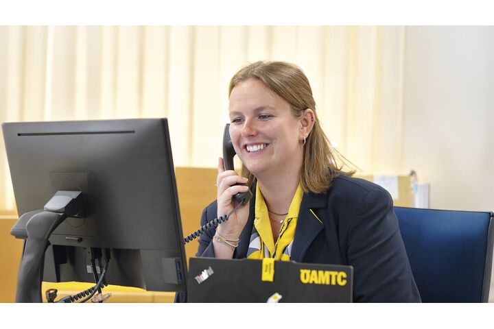 Reisebürokauffrau Katharina Wiesbauer am Telefon, wie sie auf den Computerbildschirm blickt.