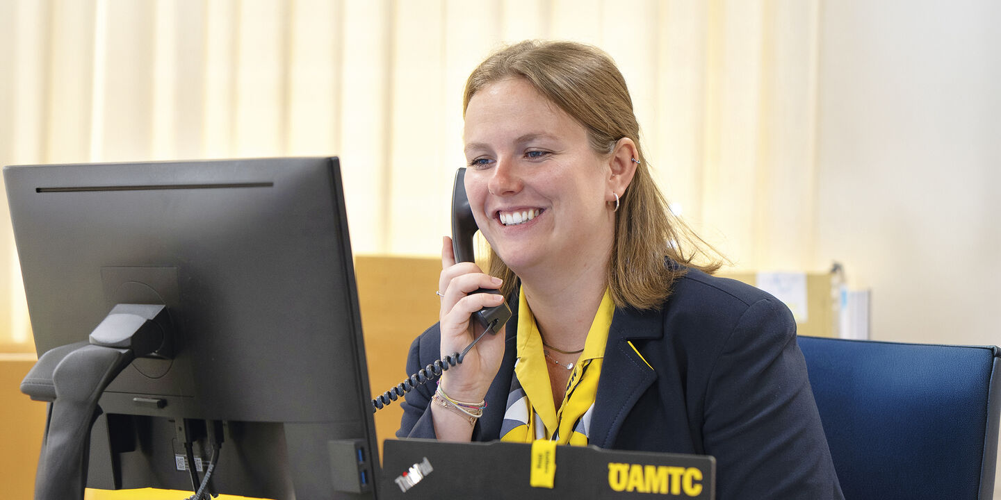 Reisebürokauffrau Katharina Wiesbauer am Telefon, wie sie auf den Computerbildschirm blickt.