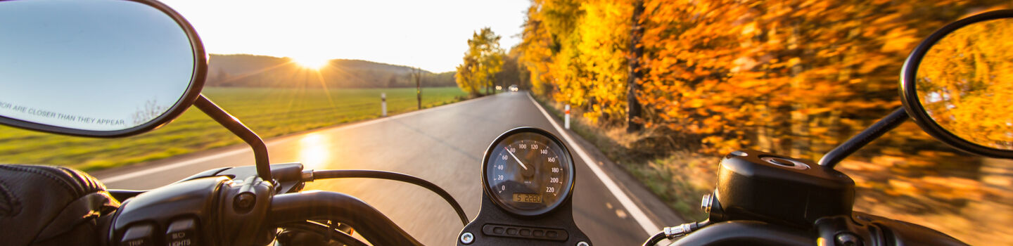 Motorradausfahrt bei sonnigem Herbstwetter. Blick aus Sicht des Fahrers auf die Straße.