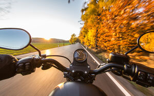 Motorradausfahrt bei sonnigem Herbstwetter. Blick aus Sicht des Fahrers auf die Straße.