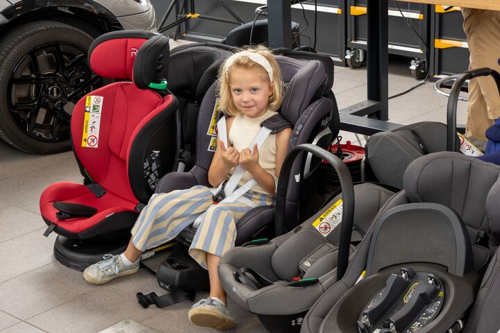 Eines der Testkinder posiert für ein Foto, während es in einem Kindersitz sitzt.