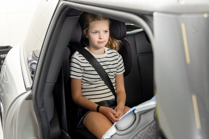 Eines der Testkinder posiert für ein Foto, während es in einem Kindersitz sitzt.