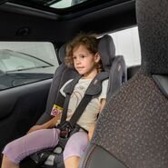 Eines der Testkinder posiert für ein Foto, während es in einem Kindersitz sitzt.