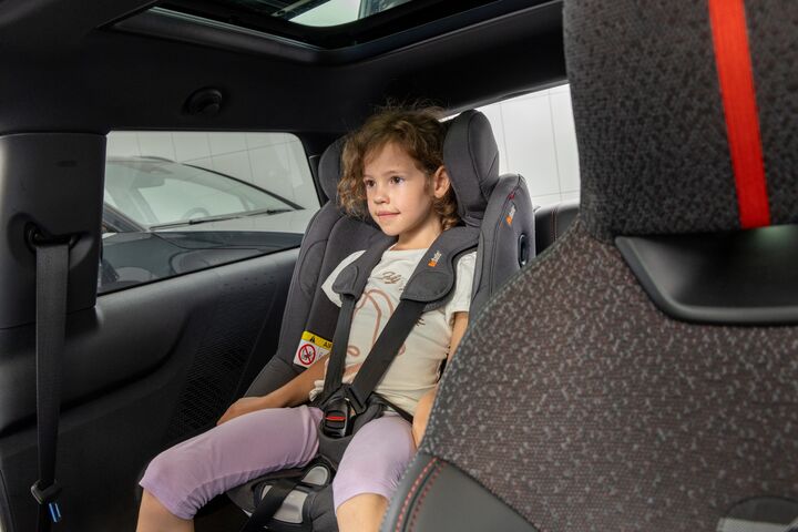 Eines der Testkinder posiert für ein Foto, während es in einem Kindersitz sitzt.