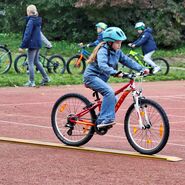 Ein Kind balanciert sein Fahrrad auf einer schmalen Fahrspur