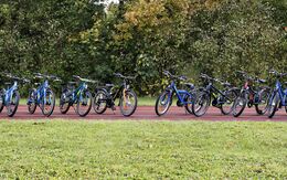 12 Kinderfahrräder mit  20 Zoll Felgengröße stehen auf einem Weg im Park aufgereiht.