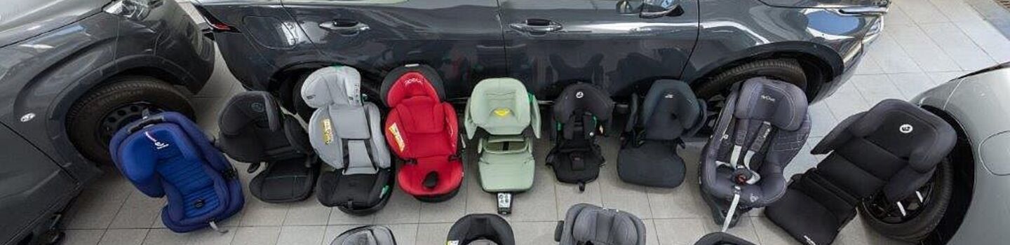 Kindersitze in unterschiedlichen Größen und Farben stehen am Boden einer Testhalle.