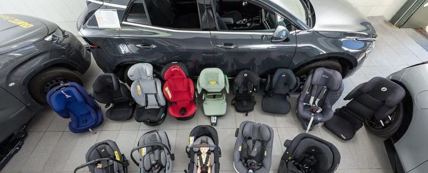 Kindersitztest 2025 (Herbst) Kindersitze in unterschiedlichen Größen und Farben stehen am Boden einer Testhalle.