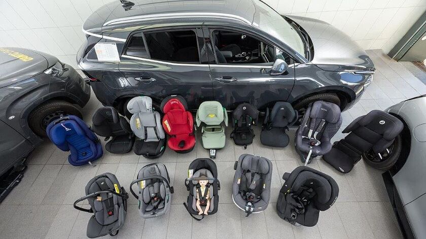 Kindersitze in unterschiedlichen Größen und Farben stehen am Boden einer Testhalle.