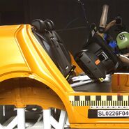 Das Bild zeigt einen Kindersitztest, dabei wird der Kindersitz, indem ein Dummie sitzt, aus der Basishalterung geschleudert. 