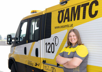 Es ist eine Frau in ÖAMTC-Kleidung zu sehen. Sie lehnt an einem Pannenfahrzeug.