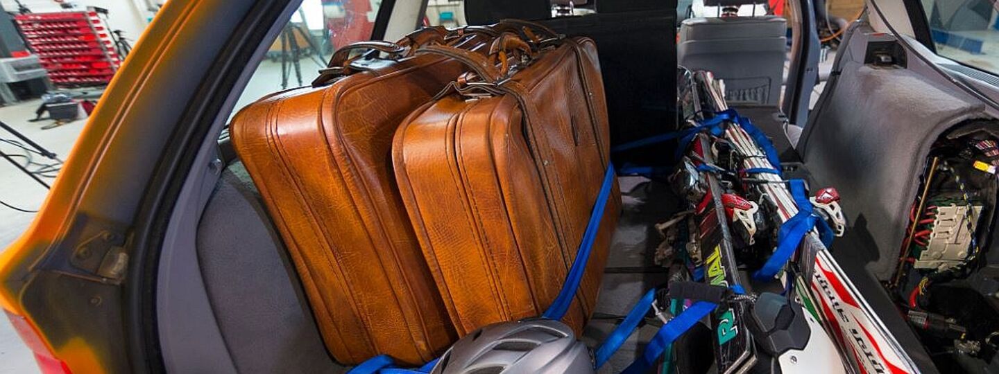 Offener Auto-Kofferraum. Das Auto ist für den Winterurlaub mit Koffer, Ski, Helme beladen. Die Gurte sind lose um die Ski gelegt. Das Auto befindet sich in einem Testzentrum.