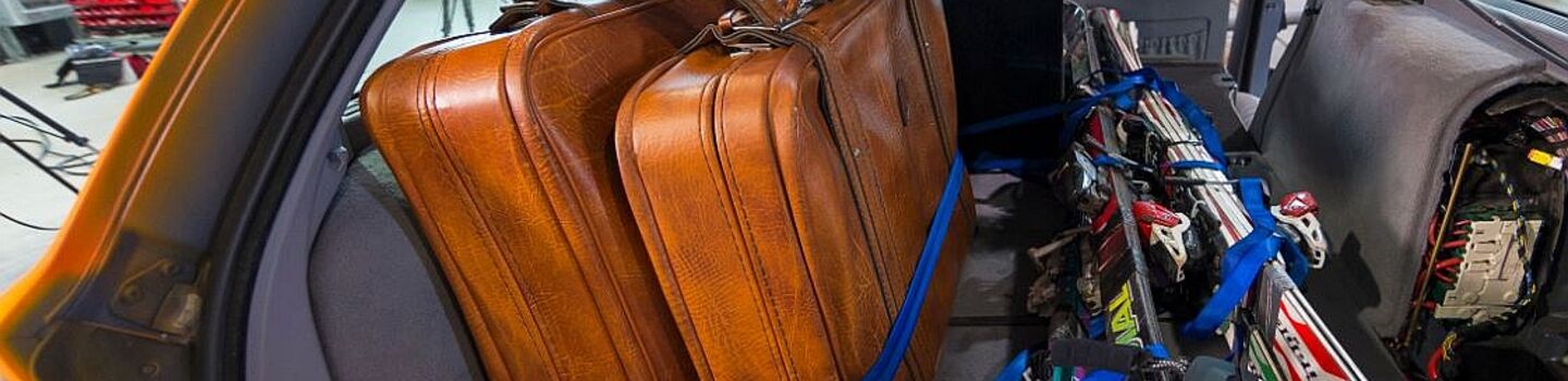 Offener Auto-Kofferraum. Das Auto ist für den Winterurlaub mit Koffer, Ski, Helme beladen. Die Gurte sind lose um die Ski gelegt. Das Auto befindet sich in einem Testzentrum.