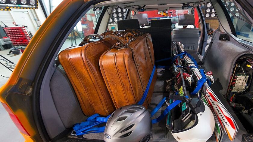 Offener Auto-Kofferraum. Das Auto ist für den Winterurlaub mit Koffer, Ski, Helme beladen. Die Gurte sind lose um die Ski gelegt. Das Auto befindet sich in einem Testzentrum.