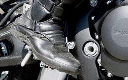 Ein schwarzer Motorradstiefel steigt in die Motorradbremse.